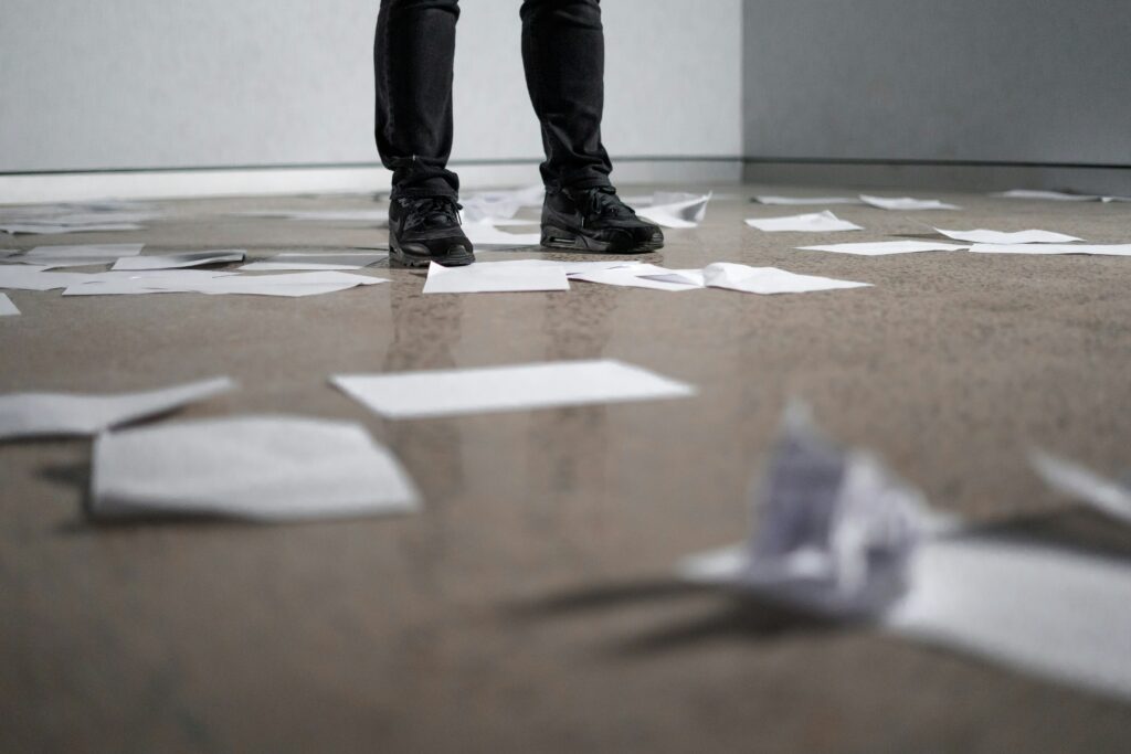 Legs standing on a floor covered in strewn and balled up paper